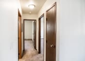 Thumbnail 15 of 17 - Bismarck, ND Rosser Apartments. a corridor with three doors and a carpeted floor