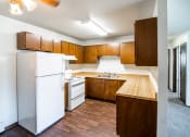 Thumbnail 10 of 17 - Bismarck, ND Rosser Apartments. a kitchen with a white refrigerator freezer next to a white stove top oven
