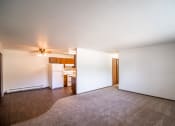 Thumbnail 8 of 17 - Bismarck, ND Rosser Apartments. an empty living room with a kitchen in the background