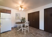 Thumbnail 3 of 17 - Bismarck, ND Rosser Apartments. A dining room with a table and two chairs. The overhead fan and light brighten the room. The entrance to the unit is next to a large closet for shoes and coats to be hung up.