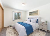 Thumbnail 3 of 16 - Sierra Ridge Apartments in Bismarck, ND | The room showcases a peaceful ambiance with a cozy bed, stylish furnishings, and soft lighting from the window
