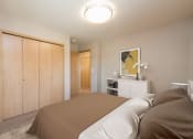 Thumbnail 8 of 11 - Bismarck, ND Stonefield Townhomes. The room features a comfortable bed, stylish furnishings, and a warm color palette, creating a relaxing atmosphere. The wardrobe provides storage space for the small room.