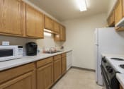 Thumbnail 5 of 7 - a kitchen with white appliances and wooden cabinets. Bismarck, ND Bradbury Apartments
