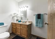 Thumbnail 9 of 10 - Bismarck, ND Brandon Apartments a bathroom with a toilet sink and mirror