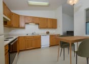 Thumbnail 2 of 26 - a kitchen with white appliances and wooden cabinets with a small dining table. Fargo, ND Bridgeport Apartments