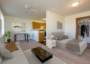 Thumbnail 6 of 26 - a studio apartment furnished with a couch, bed, dining table, with a kitchen in the background. Fargo, ND Bridgeport Apartments