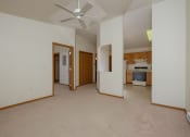 Thumbnail 19 of 26 - a living room with a ceiling fan and a kitchen in the background. Fargo, ND Bridgeport Apartments