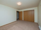Thumbnail 15 of 26 - a bedroom with a closet and carpeted floors. Fargo, ND Bridgeport Apartments