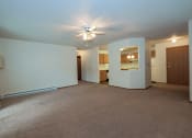 Thumbnail 13 of 26 - a living room with a ceiling fan and a kitchen in the background. Fargo, ND Bridgeport Apartments