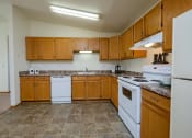 Thumbnail 8 of 26 - a kitchen with white appliances and wooden cabinets. Fargo, ND Bridgeport Apartments