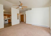 Thumbnail 7 of 26 - a living room with a ceiling fan and a kitchen in the background. Fargo, ND Bridgeport Apartments