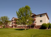 Thumbnail 26 of 26 - the outside of a three level apartment building with two trees out front. Fargo, ND Bridgeport Apartments