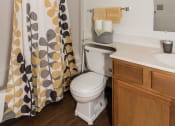 Thumbnail 15 of 19 - Grand Forks, ND Bristol Park Apartments. a bathroom with a white sink and toilet next to a shower curtain
