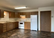 Thumbnail 9 of 13 - an empty kitchen with a refrigerator and a sink. Fargo, ND Brookfield Apartments