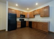 Thumbnail 10 of 23 - a kitchen with wooden cabinets and a black refrigerator. Fargo, ND North Sky Apartments