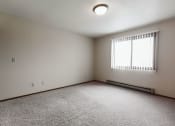 Thumbnail 8 of 11 - Grand Forks, ND Carling Manor Apartments. a bedroom with a large window and beige carpet