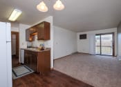 Thumbnail 30 of 41 - an empty living room with a kitchen and a door to a balcony. Fargo, ND Carlton Place Apartments