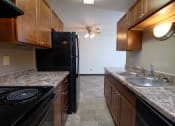 Thumbnail 24 of 41 - a kitchen with black appliances and granite counter tops and wooden cabinets. Fargo, ND Carlton Place Apartments