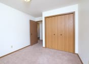 Thumbnail 23 of 41 - a bedroom with a closet and a door to a hallway. Fargo, ND Carlton Place Apartments