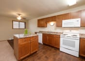 Thumbnail 5 of 13 - an empty kitchen with white appliances and wooden cabinets. Fargo, ND Cedars 2 Apartments