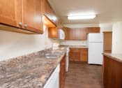 Thumbnail 6 of 13 - a kitchen with marble counter tops and wooden cabinets and a white refrigerator. Fargo, ND Cedars 2 Apartments