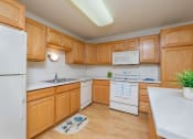 Thumbnail 6 of 20 - A kitchen with white appliances and wooden cabinets