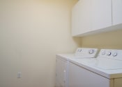 Thumbnail 11 of 20 - A washer and dryer in a laundry room with white cabinets