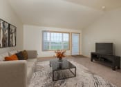 Thumbnail 2 of 20 - A living room with a couch, coffee table, and tv with an entry door and a window. West Fargo, ND Charleswood Townhomes.