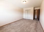 Thumbnail 7 of 19 - Grand Forks, ND Cherry Creek Apartments. A bedroom with white walls and a carpeted floor