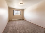 Thumbnail 8 of 19 - Grand Forks, ND Cherry Creek Apartments. A bedroom in unit 223 that has a window, white walls, and carpeted floors