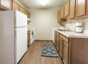 Thumbnail 6 of 19 - Grand Forks, ND Cherry Creek Apartments. A kitchen with a rug by the sink and white appliances.