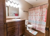 Thumbnail 17 of 19 - Grand Forks, ND Cherry Creek Apartments. A decorated bathroom with dark wood cabinets and a tub