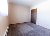 Thumbnail 16 of 19 - Grand Forks, ND Cherry Creek Apartments. A bedroom with a closet, window, white walls, and carpeted floors