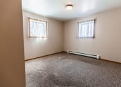 Thumbnail 15 of 19 - Grand Forks, ND Cherry Creek Apartments. A bedroom with a closet, 2 windows, white walls, and carpeted floors