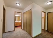 Thumbnail 8 of 10 - the view of a bedroom and bathroom from the hallway of a home with wooden doors. Fargo, ND Chestnut Ridge Apartments