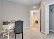 Thumbnail 58 of 83 - a bedroom with a desk with a chair and a door to a bathroom.  Circle Pines, MN Lexington Lofts