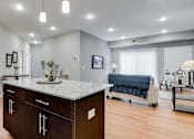 Thumbnail 55 of 83 - a kitchen with an island and a living room with a couch. Circle Pines, MN Lexington Lofts