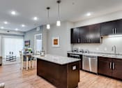 Thumbnail 46 of 83 - a kitchen with an island and a living room with a couch. Circle Pines, MN Lexington Lofts