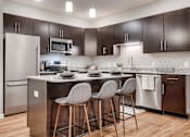 Thumbnail 34 of 83 - a kitchen with stainless steel appliances and a counter with three bar stools. Circle Pines, MN Lexington Lofts