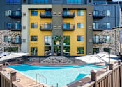 Thumbnail 82 of 83 - a swimming pool at an apartment building with a pool and umbrellas. Circle Pines, MN Lexington Lofts