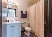 Thumbnail 6 of 8 - Grand Forks, ND Claremont Apartments. A bathroom with white cabinets a sink, toilet, and bathtub.