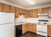 Thumbnail 4 of 10 - Grand Forks, ND Columbia West Apartments. a kitchen with white appliances and wooden cabinets