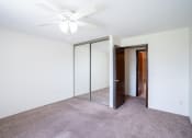 Thumbnail 9 of 14 - a bedroom with a ceiling fan and mirrored closet. Coon Rapids, MN Robinwood Apartments