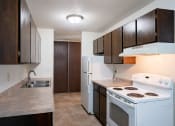 Thumbnail 7 of 14 - an empty kitchen with white appliances and wooden cabinets. Coon Rapids, MN Robinwood Apartments