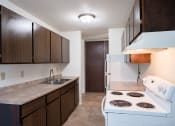 Thumbnail 8 of 14 - a kitchen with white appliances and wooden cabinets and a white stove. Coon Rapids, MN Robinwood Apartments