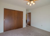 Thumbnail 26 of 42 - a bedroom with a closet and a ceiling fan. Fargo, ND Country Club Apartments.