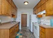 Thumbnail 24 of 42 - a kitchen with white appliances and wooden cabinets. Fargo, ND Country Club Apartments.