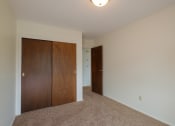 Thumbnail 23 of 42 - a bedroom with a closet and a door to a hallway. Fargo, ND Country Club Apartments.