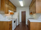Thumbnail 21 of 42 - an empty kitchen with white appliances and wooden cabinets. Fargo, ND Country Club Apartments.