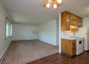 Thumbnail 19 of 42 - an empty living room with a kitchen with a stove and refrigerator. Fargo, ND Country Club Apartments.